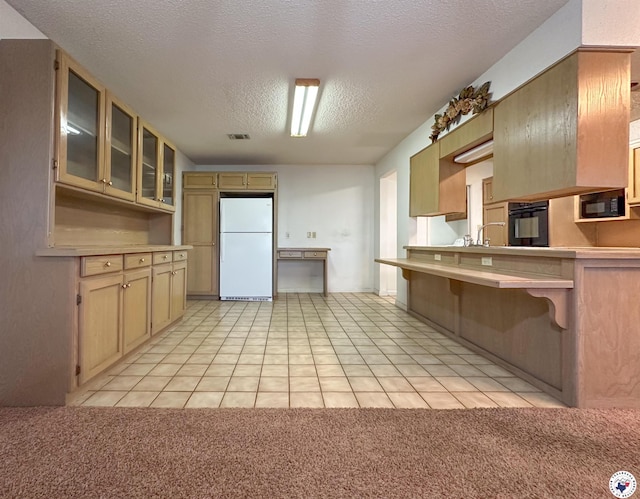 kitchen with light countertops, glass insert cabinets, a textured ceiling, and black appliances