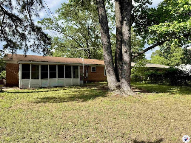 1205 W 40th St, Texarkana, TX 75503 - back of house featuring a sunroom, a lawn, and brick siding