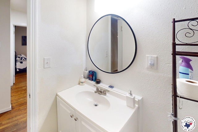 1205 W 40th St, Texarkana, TX 75501 - bathroom with wood finished floors, vanity, and a textured wall
