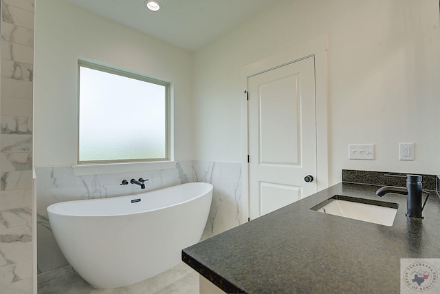 bathroom with a washtub, tile walls, and vanity