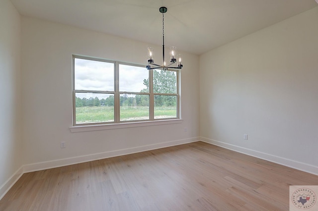 unfurnished room featuring a chandelier and light hardwood / wood-style flooring