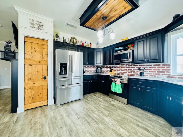 kitchen with visible vents, light wood finished floors, stainless steel appliances, hanging light fixtures, and light countertops