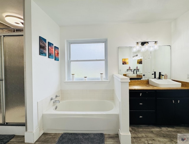 bathroom with vanity, a shower stall, a garden tub, and wood finished floors