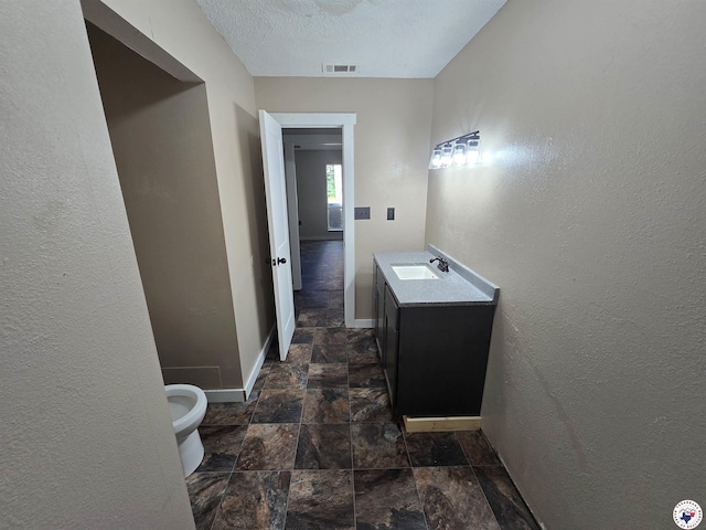 1405 S Fulton St, Hope, AR 71801 - bathroom with stone finish floors, vanity, toilet, baseboards, and a textured wall