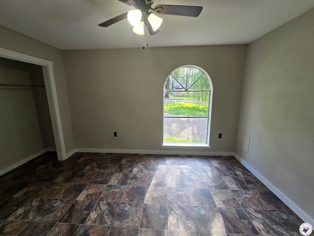 1405 S Fulton St, Hope, AR 71801 - unfurnished bedroom with baseboards, a textured ceiling, dark stone finish floors, and a ceiling fan