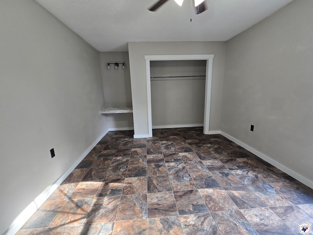 1405 S Fulton St, Hope, AR 71801 - unfurnished bedroom featuring baseboards, stone finish floors, a ceiling fan, and a closet