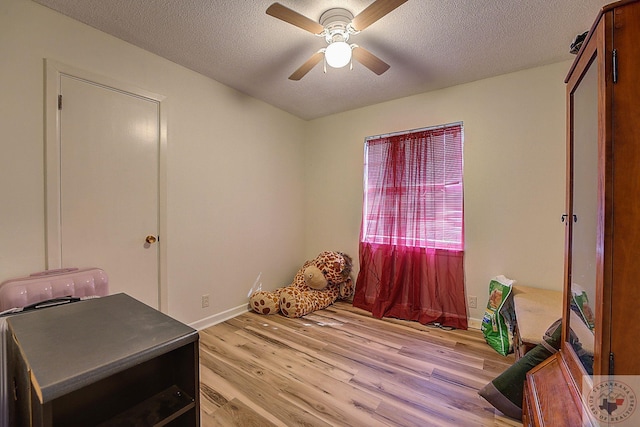 bedroom with a textured ceiling, light hardwood / wood-style flooring, and ceiling fan