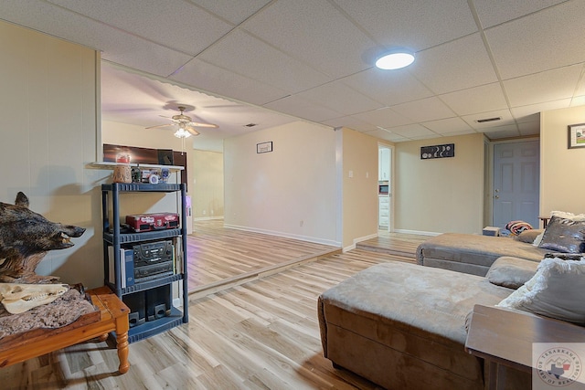 living room featuring hardwood / wood-style flooring, a paneled ceiling, and ceiling fan