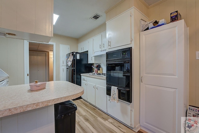 kitchen with white cabinetry, black appliances, and light hardwood / wood-style flooring