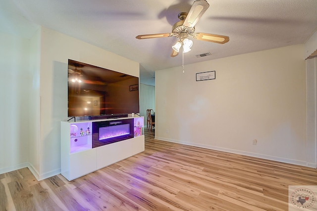 living room featuring ceiling fan, light hardwood / wood-style floors, and a textured ceiling