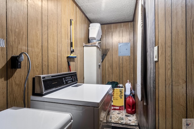 washroom with wooden walls, a textured ceiling, and washer and dryer