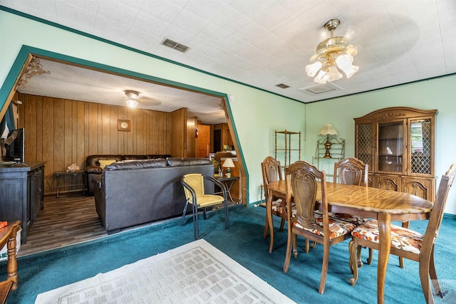 carpeted dining space featuring wood walls