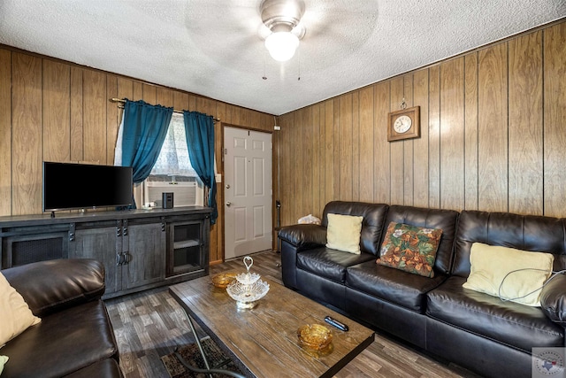 living room featuring cooling unit, dark hardwood / wood-style flooring, wood walls, and a textured ceiling