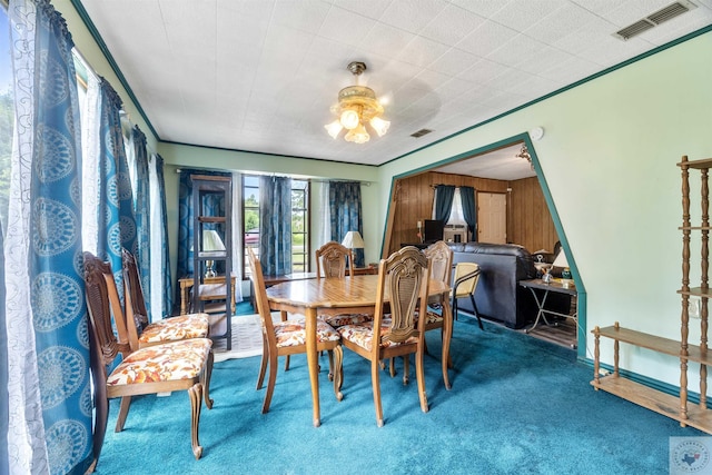 dining room featuring wooden walls and carpet