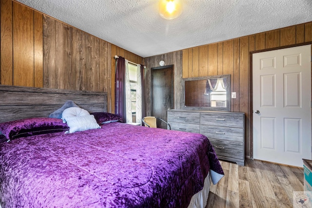 bedroom featuring wooden walls, a textured ceiling, and multiple windows