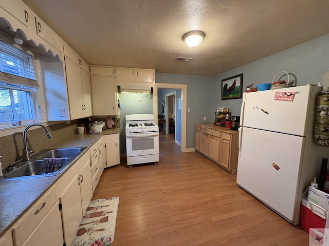 kitchen featuring white appliances, visible vents, a sink, a textured ceiling, and light wood-type flooring