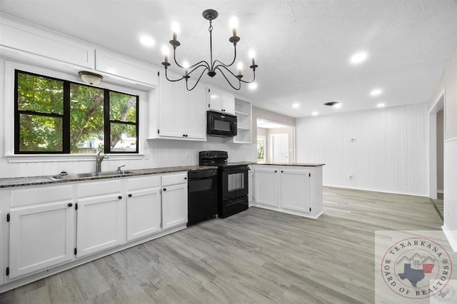 kitchen featuring black appliances, white cabinetry, sink, hanging light fixtures, and light wood-type flooring