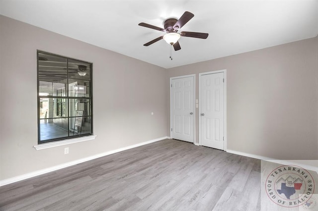 unfurnished bedroom featuring ceiling fan, multiple closets, and light wood-type flooring