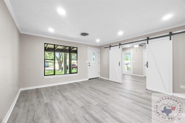 entrance foyer featuring ornamental molding, light hardwood / wood-style floors, and a barn door