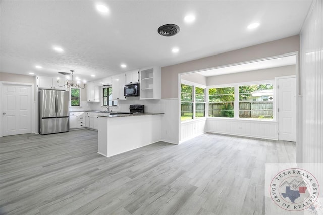 kitchen featuring kitchen peninsula, light hardwood / wood-style flooring, pendant lighting, stainless steel fridge, and white cabinetry