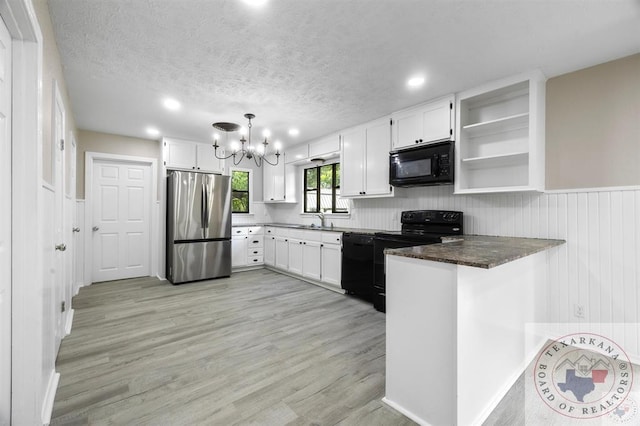 kitchen with black appliances, white cabinetry, hanging light fixtures, light hardwood / wood-style flooring, and kitchen peninsula