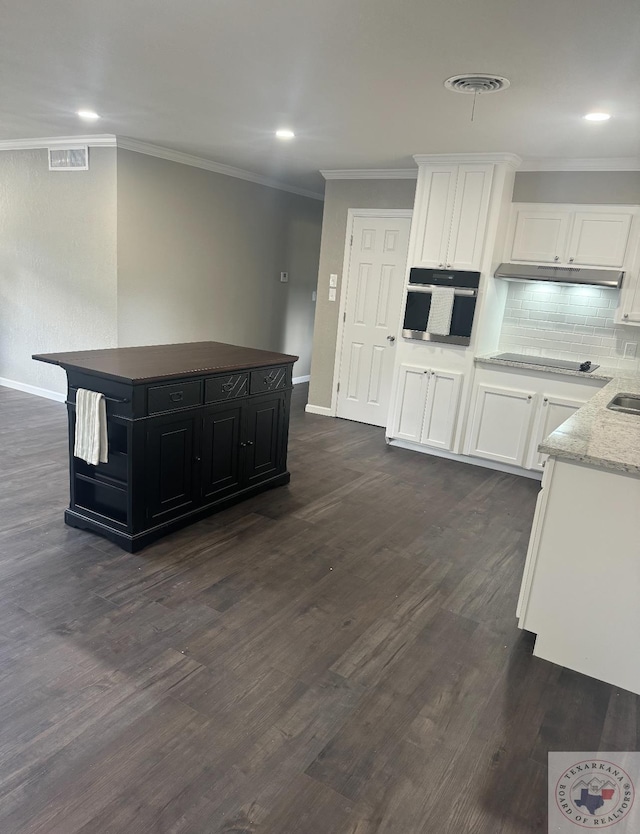 kitchen with white cabinetry, tasteful backsplash, oven, black electric cooktop, and a kitchen island