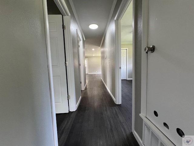 hallway featuring ornamental molding, dark wood-style flooring, and baseboards