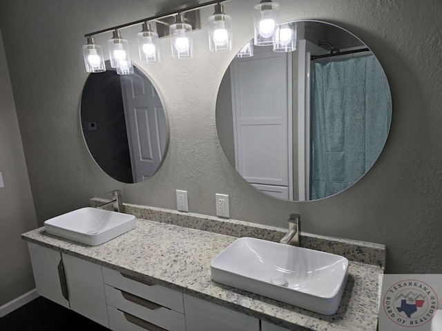 full bath with curtained shower, a sink, and a textured wall