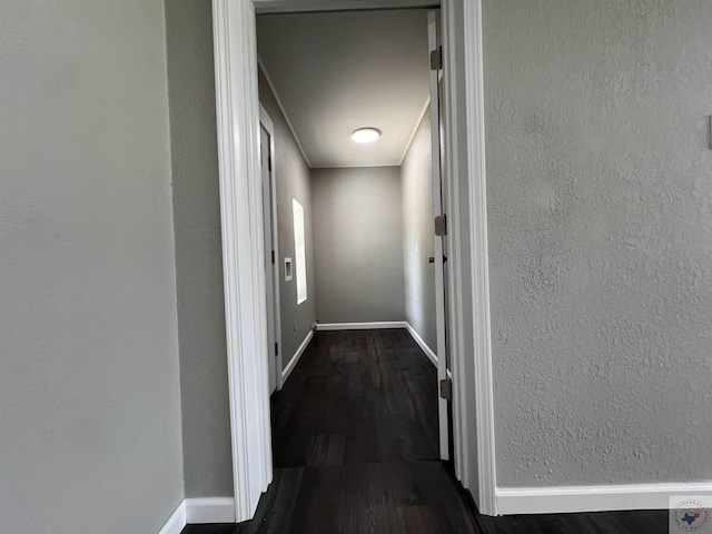 hallway with baseboards, dark wood finished floors, and a textured wall