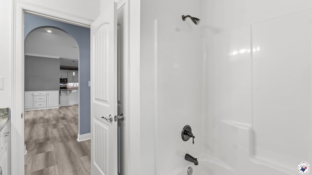full bath with wood finished floors, vanity, ornamental molding, and shower / bathtub combination