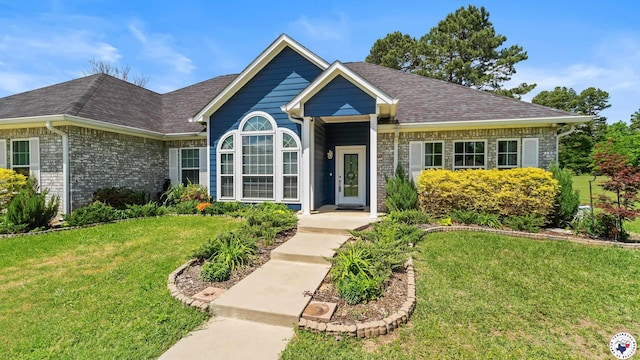 single story home featuring brick siding, a shingled roof, and a front yard