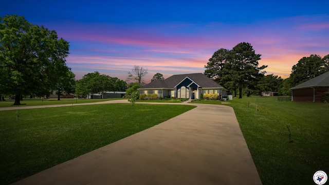 view of front of property with a yard and curved driveway