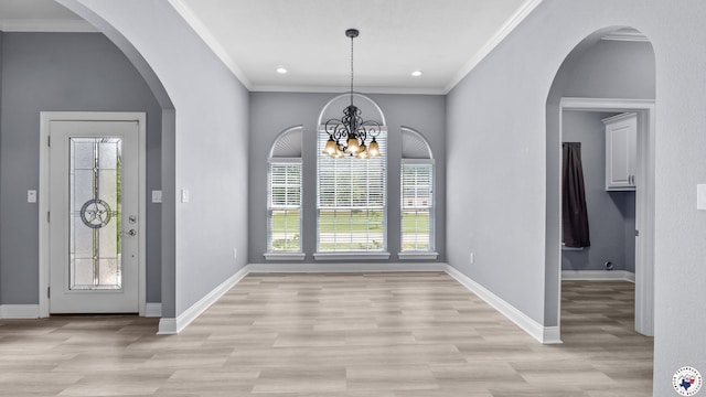 entrance foyer featuring light wood-style flooring, crown molding, baseboards, and a notable chandelier
