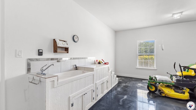 bathroom featuring concrete floors, a garden tub, and baseboards