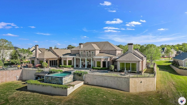 back of house featuring a chimney, a yard, a patio area, and a balcony