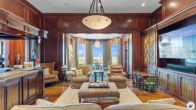 sitting room with wood walls, wood finished floors, and ornamental molding