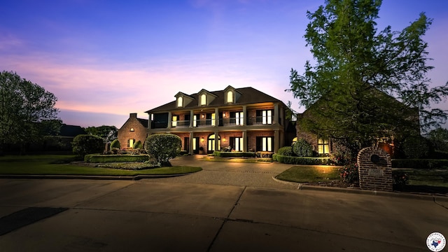 georgian-style home featuring a balcony, curved driveway, and brick siding