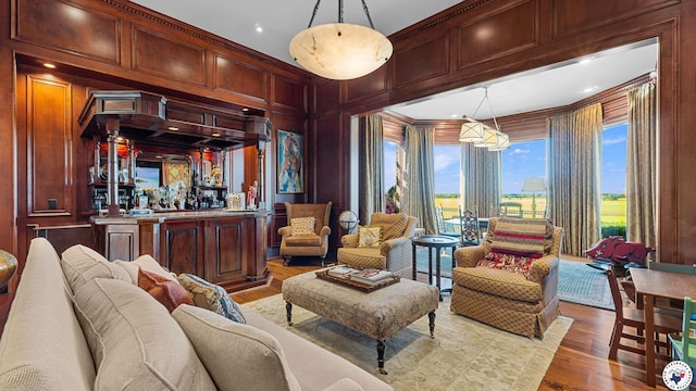 interior space with wood walls, indoor bar, wood finished floors, and ornamental molding