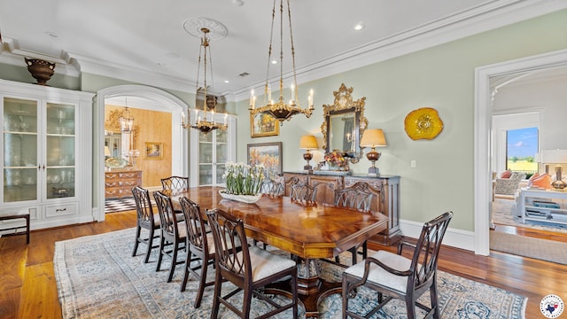 dining room with visible vents, wood finished floors, a chandelier, and crown molding