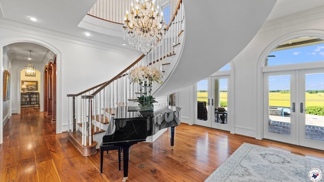 foyer with wood finished floors, french doors, stairway, and ornamental molding