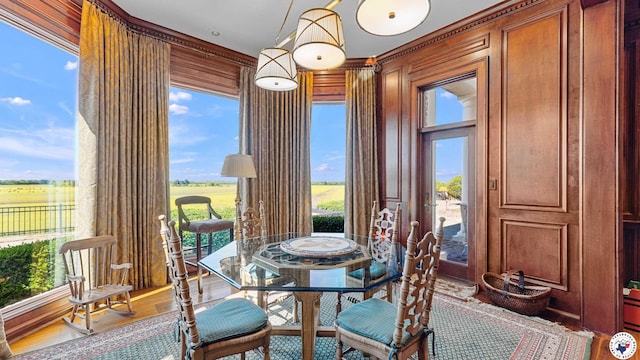 dining area featuring wood finished floors, wood walls, and ornamental molding