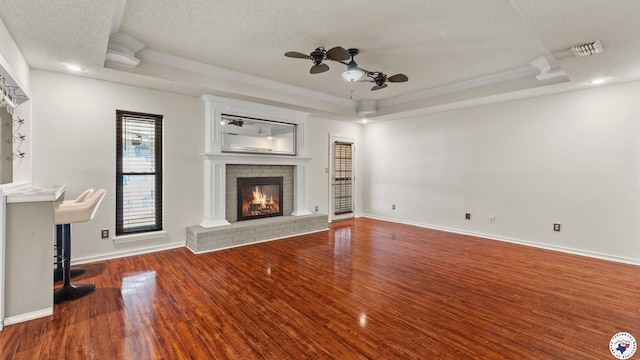 208 Jeffrey Ln, Wake Village, TX 75501 - unfurnished living room featuring a brick fireplace, a ceiling fan, ornamental molding, wood finished floors, and a tray ceiling