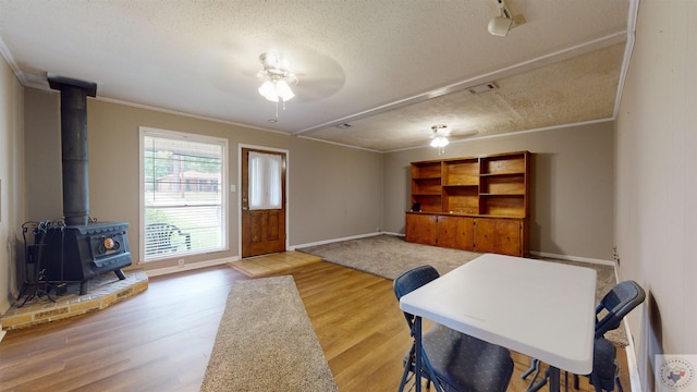 interior space with a wood stove, hardwood / wood-style floors, crown molding, and a textured ceiling