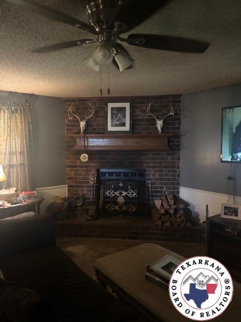 4903 Charleston St, Texarkana, AR 71854 - living room featuring a large fireplace, a ceiling fan, and a textured ceiling