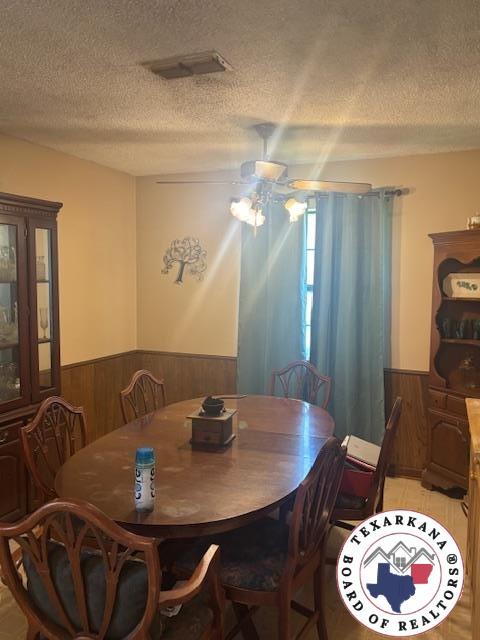 4903 Charleston St, Texarkana, AR 71854 - dining area with wainscoting, a textured ceiling, wood walls, and ceiling fan
