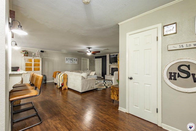 205 S Park Dr, New Boston, TX 75570 - living room featuring ceiling fan, dark wood-style floors, ornamental molding, a fireplace with raised hearth, and baseboards