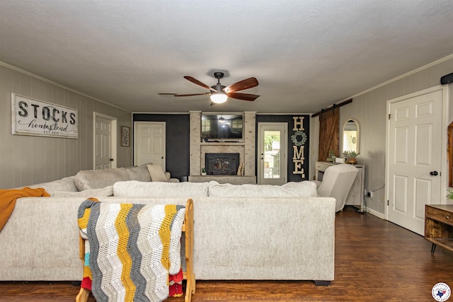 205 S Park Dr, New Boston, TX 75570 - living room featuring crown molding, dark wood-style flooring, a barn door, a ceiling fan, and a large fireplace