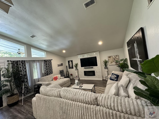 living room with a large fireplace, vaulted ceiling, and dark hardwood / wood-style floors