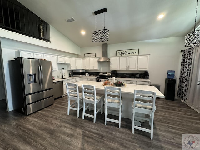 kitchen with white cabinetry, hanging light fixtures, sink, stainless steel appliances, and wall chimney exhaust hood