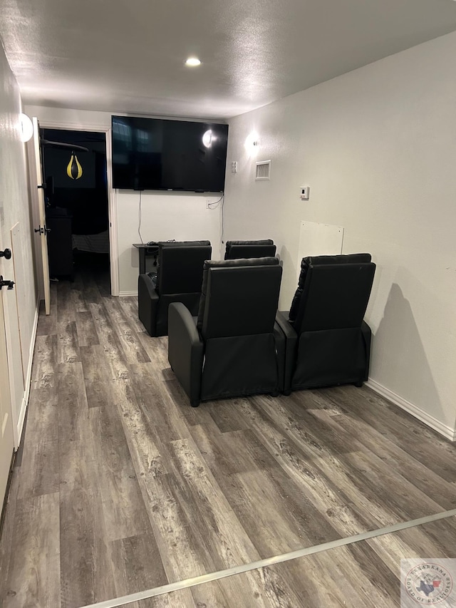 cinema room featuring wood finished floors, visible vents, and baseboards